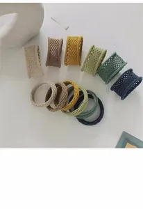 Vue macro de six chouchous élastiques aux couleurs Morandi avec texture en maille ajourée et haute élasticité