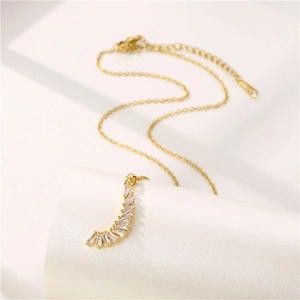 Elegant gold crescent moon pendant necklace with rectangular zircon stones on white pillar