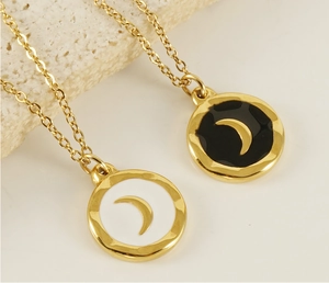 Detail of round gold-plated enamel moon pendants in black and white on stone base