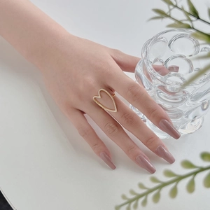 Detail of a large hollow heart ring in gold with sparkling zircons worn by a model