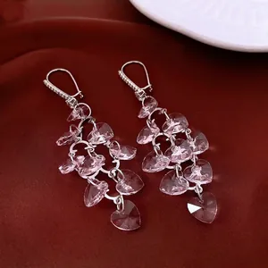 Elegant silver heart fringe earrings with pink crystal tassels on red satin background