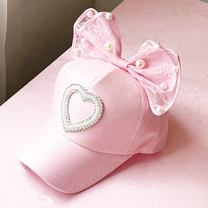 Detailed view of pink mesh baseball cap with oversized lace bow and pearl heart decoration