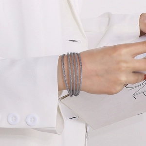 Detailed close-up of multi-layer silver-gray woven steel cable cuff on female wrist