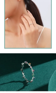 Macro shot of silver ring with colorful gemstones on a dark green background