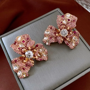 Macro shot of triangle flower earrings with pink rhinestones and gold metal base