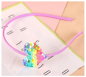 Détail d'un serre-tête violet avec un ornement de cœur en paillettes dégradé arc-en-ciel