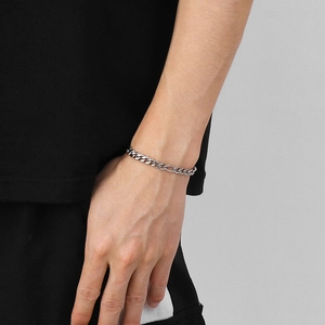 Vue détaillée d'un bracelet gourmette Figaro argenté porté au poignet, métal poli