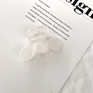 Close-up of a small milky white acrylic hair claw clip with a three-ball design on a magazine