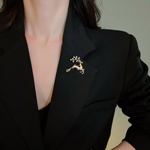 Detail einer goldenen Rentier-Brosche mit Perlen und Kristallen auf einem Sakko