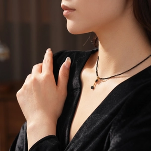Elegant black crystal beaded necklace with gold accents worn on a velvet outfit