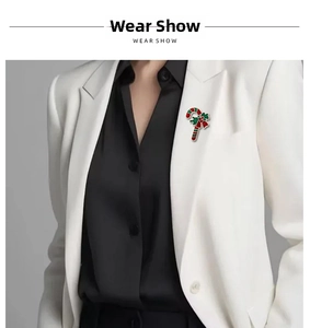 Detail of candy cane Christmas brooch with green leaves and red bow on a white suit jacket