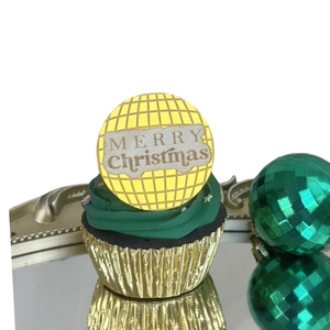 Close-up of a disco ball style Merry Christmas acrylic cake topper on a cupcake