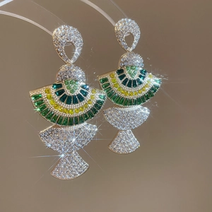 Detailed close-up of fan-shaped silver stud earrings with green and yellow crystals