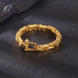 Detailed view of a gold Byzantine chain bracelet featuring a robust U-shaped shackle clasp