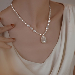 Close-up of elegant French baroque necklace featuring irregular white pearls on a model