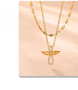 Détail du collier double couche doré avec pendentif ailes d'ange cœur et croix