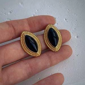 Detailed close-up of retro gold-plated stud earrings with black oval agate stones