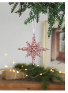 Close-up of pink glittery Christmas star ornament with hollow pattern on a tree