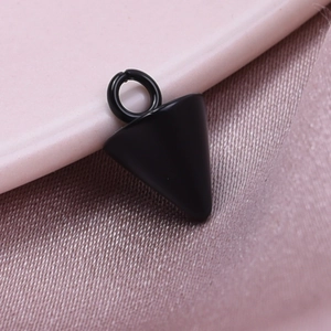 Macro shot of a black conical metal pendant on pink silk for DIY jewelry making