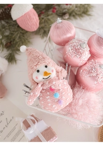 Pink Christmas plush snowman and decorative ornaments in a white metal basket