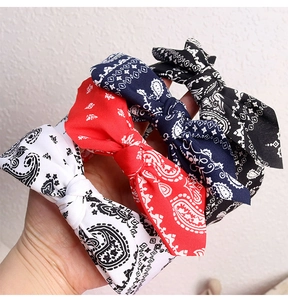 Detail of four paisley printed knot headbands in white, red, navy blue, and black colors