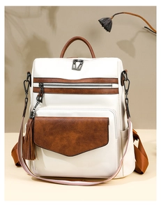 Detail of vintage bicolor backpack with tassel front pocket and contrast shoulder strap