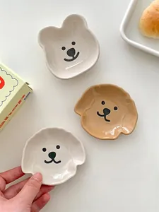 Close-up of cute bear and dog ceramic sauce dishes in cream and white tones