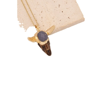 Retro bohemian necklace featuring a gold bull skull pendant with purple gemstone on stone