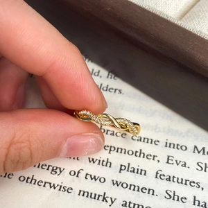 Elegant gold twisted ring with cubic zirconia accents displayed on a vintage book