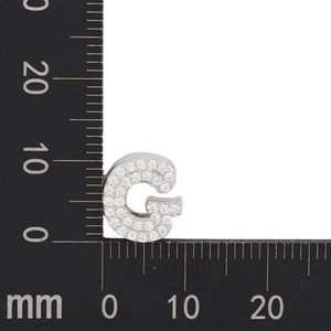 Macro shot of silver letter G pendant with zircon stones and 12mm measurement scale