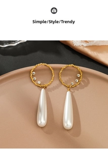 Detail of 14K gold plated teardrop pearl earrings with rhinestones on silk background