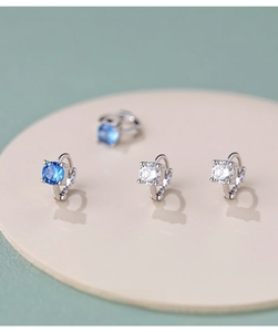 Close-up of S925 silver hoop earrings with blue and clear zircon stones on a display stand