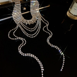 Dettaglio della collana a strati con frange di strass argentati su superficie nera lucida