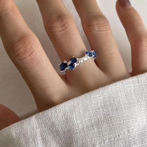 Detailed view of sterling silver ring featuring pave-set blue and white gemstones