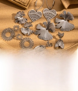 Detailed close-up of titanium steel earrings featuring ginkgo and heart shapes in steel color