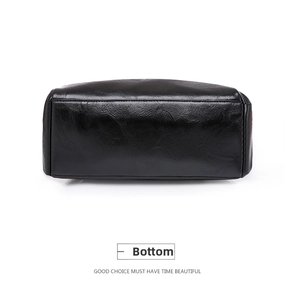 Detailed bottom view of black faux leather backpack showing stitching and wax texture