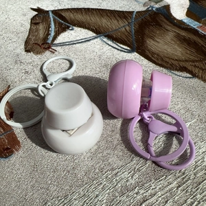 Close-up of portable white and light purple plastic spray bottles with keychains