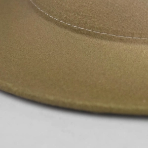 Macro detail of camel wool felt hat brim showing precise white stitching craftsmanship