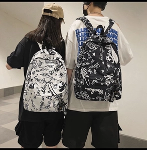 Rear view of models wearing black and white graffiti print backpacks with XBOOM straps