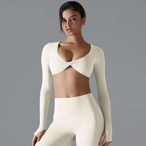 Dettaglio di un top corto a maniche lunghe bianco crema e leggings da yoga a vita alta