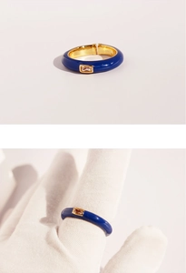 Macro view showing blue enamel gold ring with zircon inlay and on-finger wear detail