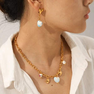 Ensemble collier et boucles d'oreilles cœur dorés portés élégamment par un modèle