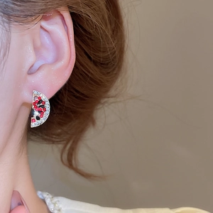 Macro shot of a sparkling rhinestone watermelon stud earring worn on the ear model