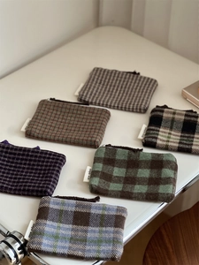 Detailed view of various plaid patterns and textures on mini tweed zipper pouches