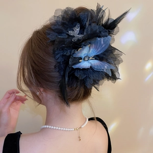 Close-up of a black floral hair claw with blue butterfly and soft feather details