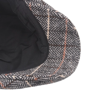 Macro view of men's herringbone tweed newsboy cap with orange windowpane pattern details