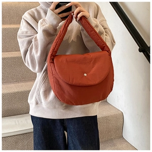 Detail of rust red quilted shoulder bag featuring fold-over flap and silver buckle detail