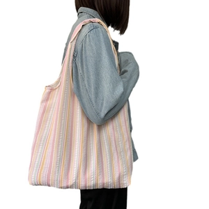 Femme portant un grand sac cabas en toile rayée texturée en tissu seersucker rose et jaune