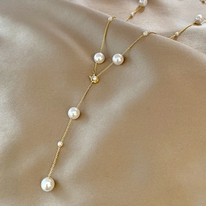 Vue détaillée du collier doré en Y avec perles dégradées sur un tissu en satin champagne