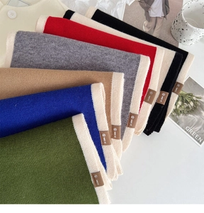Detail of multi-color knitted scarves with contrast trim and premium leather labels